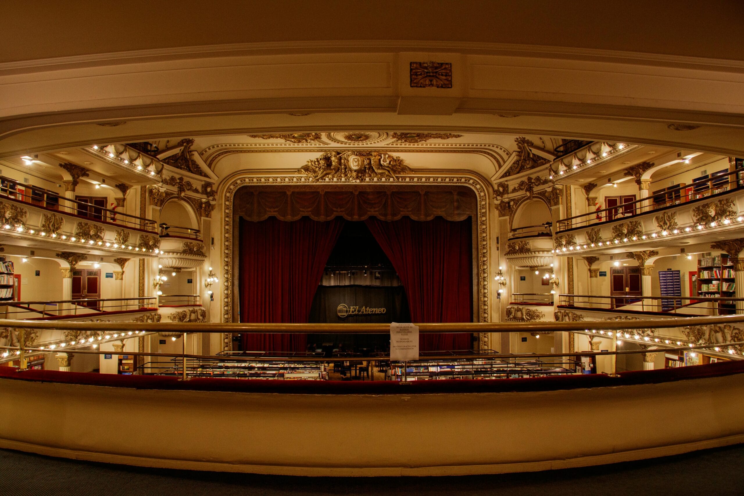The stage and curtained proscenium of El Ateneo Grand Splendid, seen from a balcony lined with bookshelves