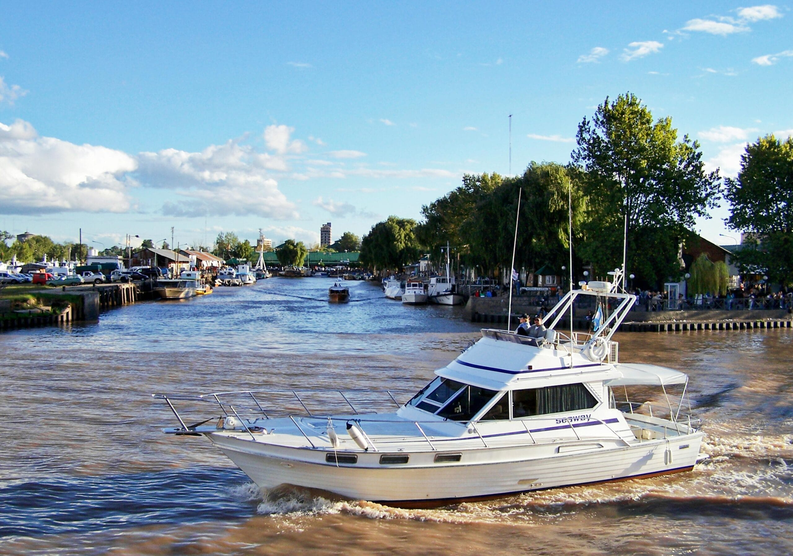A launch heading up the channel at Tigre, with boats moored along both banks