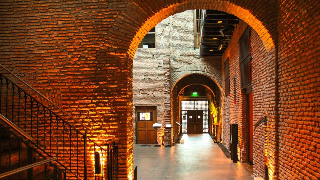 Restored brick vaults and arches lit in warm light inside the Zanjon de Granados in San Telmo