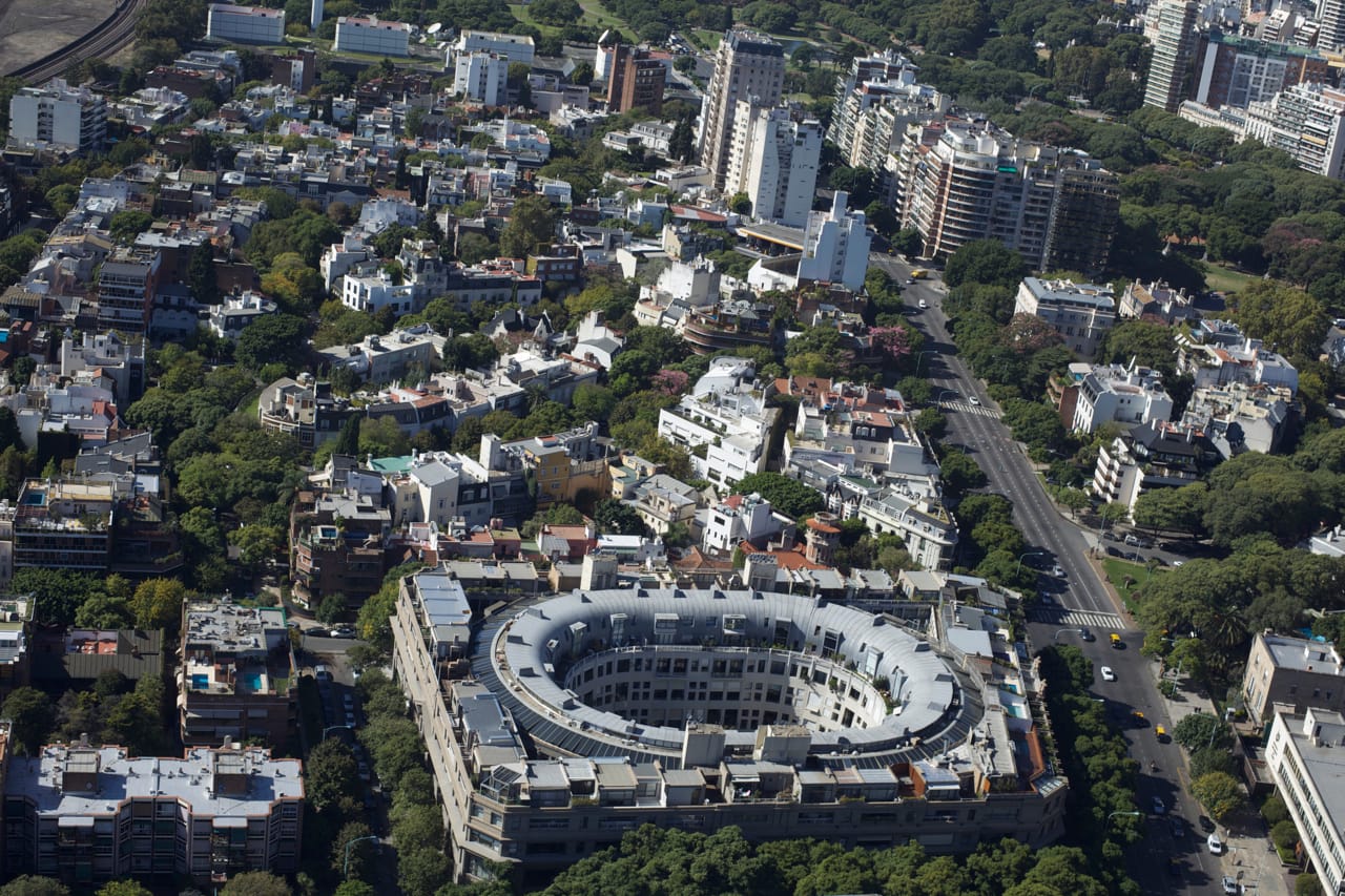 Colour aerial photograph of Palermo Chico with a round building around an oval courtyard in the middle of green, tree-lined streets